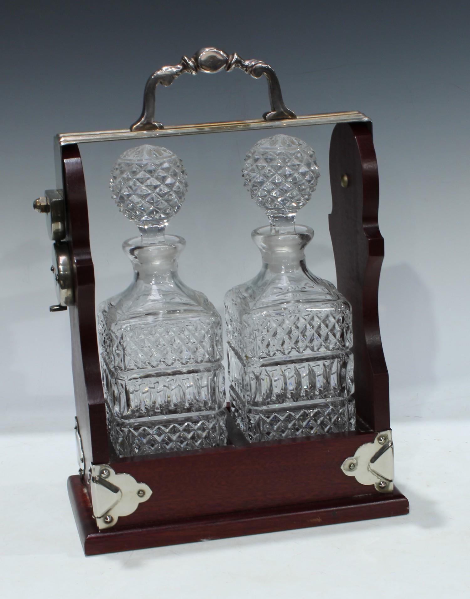 A mahogany two bottle tantalus, silver plated handle and mounts, 34cm high, 25cm wide