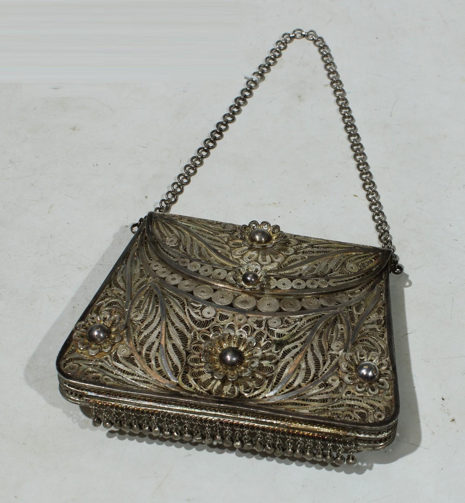 An early 20th century silver filigree evening bag, typically worked with flowerheads and scrolls,