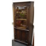 An oak corner cabinet, glazed door to top, panel door to base.