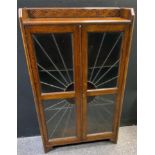 A 1930's oak sunburst twin door Art Deco display cabinet, leaded doors