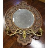 An Victorian oak oval mirror, carved with of flowers and scrolls, two brass candle sconces, 72cm