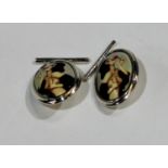 A pair of silver and enamel novelty risque cufflinks, each decorated in polychrome with a scantily