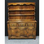 An early/mid 20th century oak dresser, outswept cornice above plate racks, the projecting base