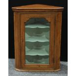 A 19th century oak wall hanging corner display cabinet, slightly outswept top above a glazed door