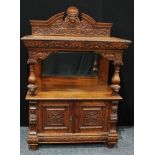 A late Victorian oak pier/side cabinet, arched pediment centred by a carved mask, above a