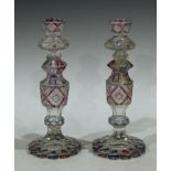A pair of Bohemian clear glass candlesticks, strawberry cut, the shaped bases engraved with