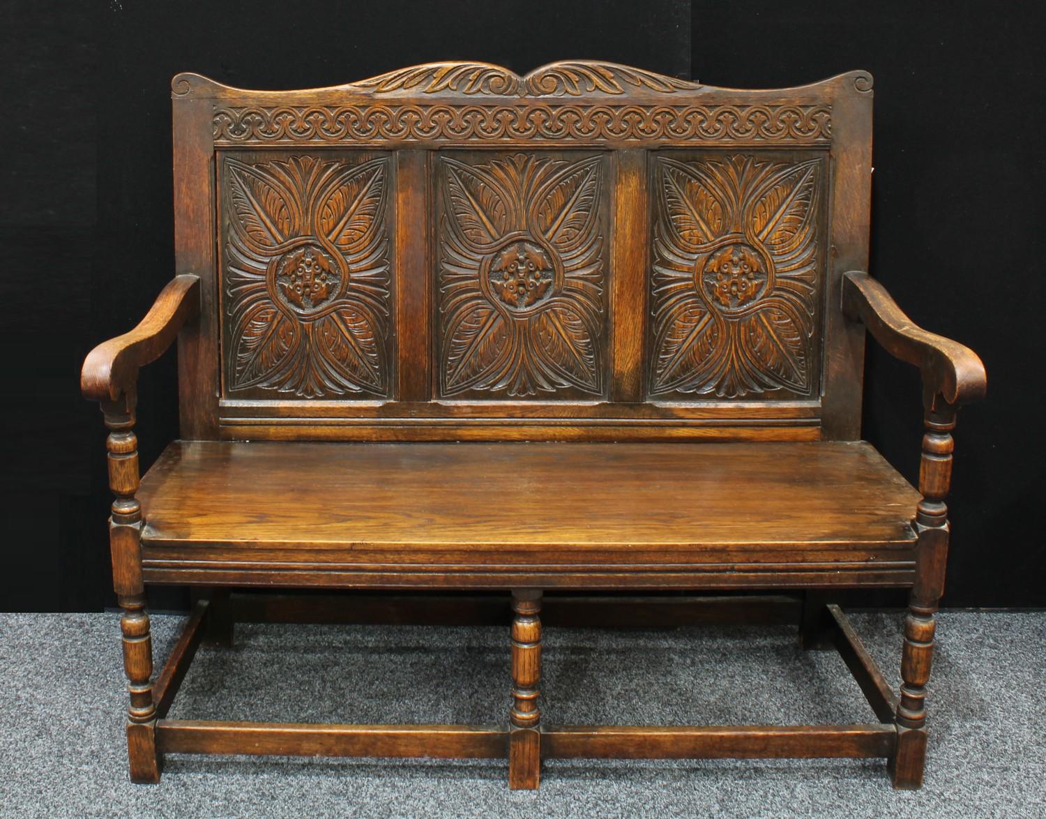 A 17th century style oak bench/settle, shaped cresting rail carved with acanthus, above a three