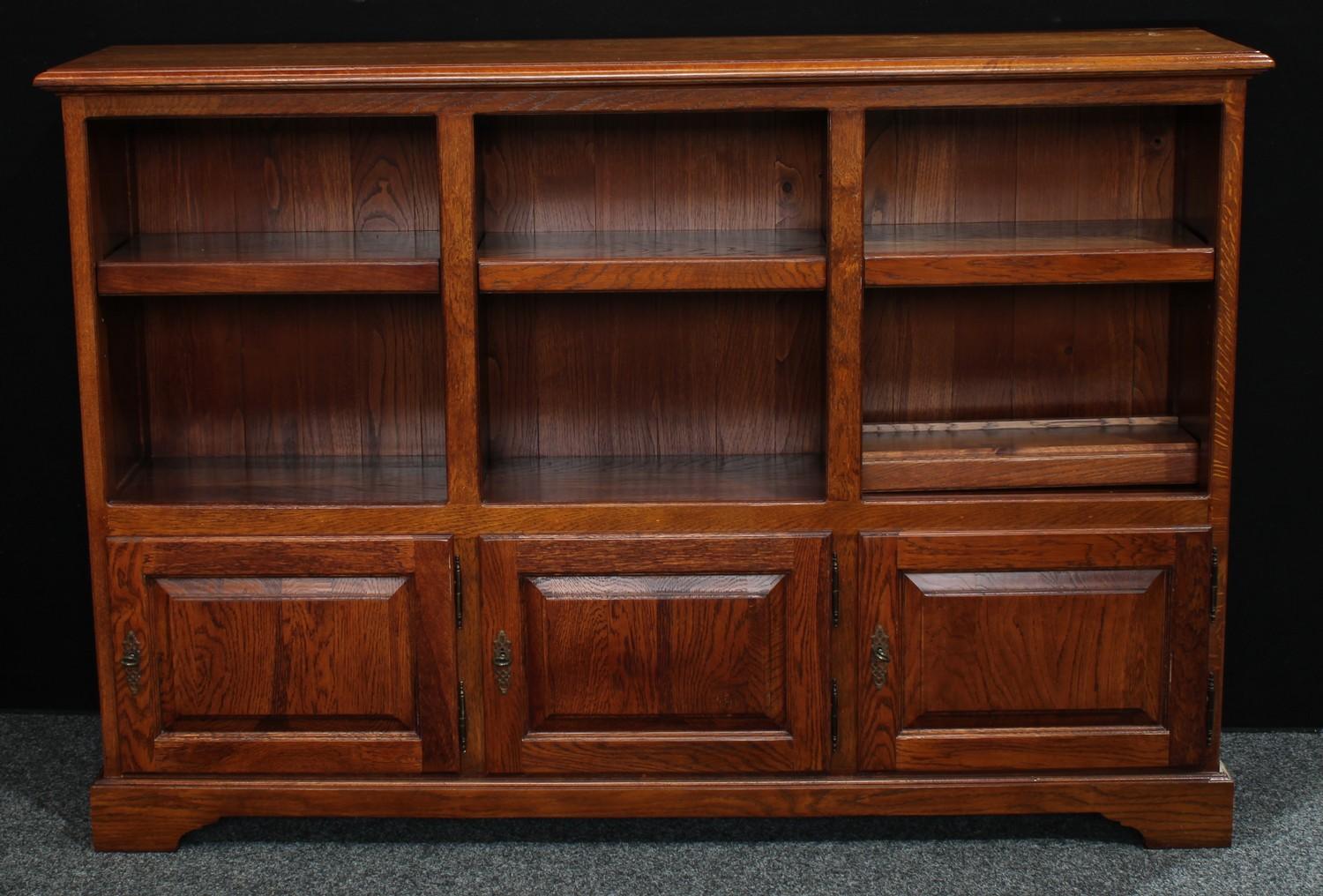 An early 20th century oak open bookcase, rectangular top above adjustable shelves and three cupboard