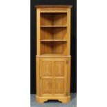 A contemporary oak corner display cabinet, outswept cornice above shelves and a lining folds