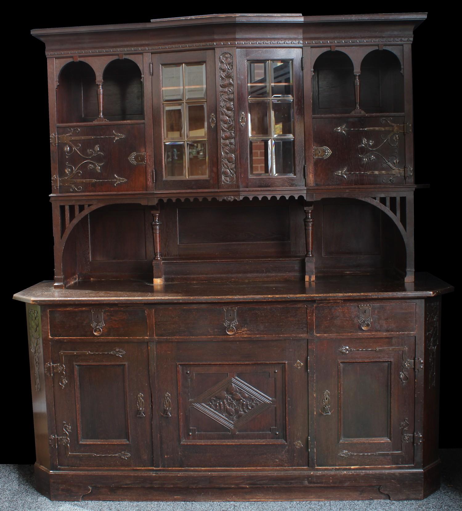 A substantial Arts & Crafts oak sideboard, outswept cornice above a pair of glazed doors enclosing