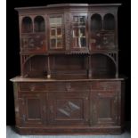 A substantial Arts & Crafts oak sideboard, outswept cornice above a pair of glazed doors enclosing