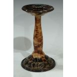 A Doulton Lambeth candlestick, tube lined with stylised leaves and scrolling foliage, in tones of