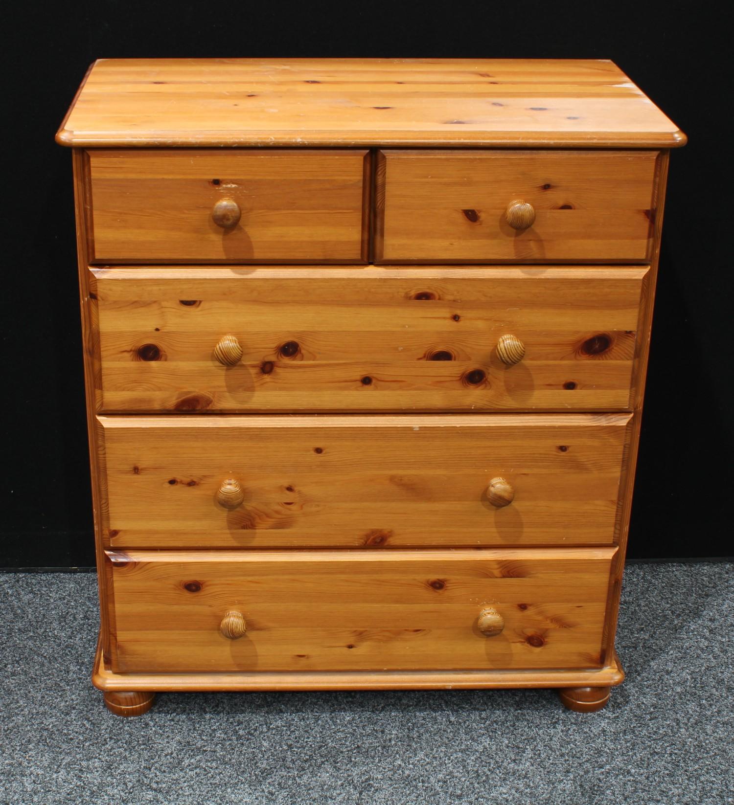 A pine chest of drawers, rounded rectangular top above two short and three long drawers, bun feet,