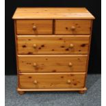 A pine chest of drawers, rounded rectangular top above two short and three long drawers, bun feet,