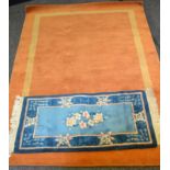 A Chinese woollen runner, with flowers in tones of blue, 120cm x 60cm; a rust woollen rug, banded