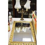 A gilt framed wall mirror; a two branch figuratively table lamp.