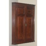 An 18th century oak fluted splay fronted corner cupboard, fielded panelled doors, shaped shelves,