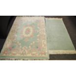 A rectangular rug - central floral medallion, pale green ground with multi tone border fringe