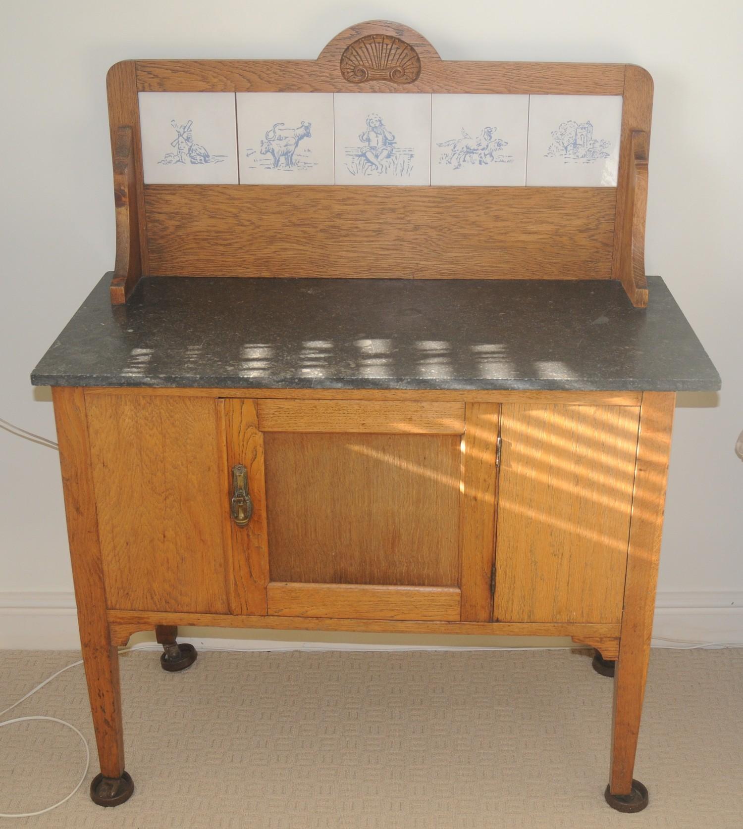 An early 20th century oak washstand, with four tiles to splash back, marble top, single door,