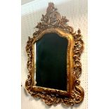 A reproduction gilt framed wall mirror, moulded and swagged pediment to shaped, arched top. 133cm