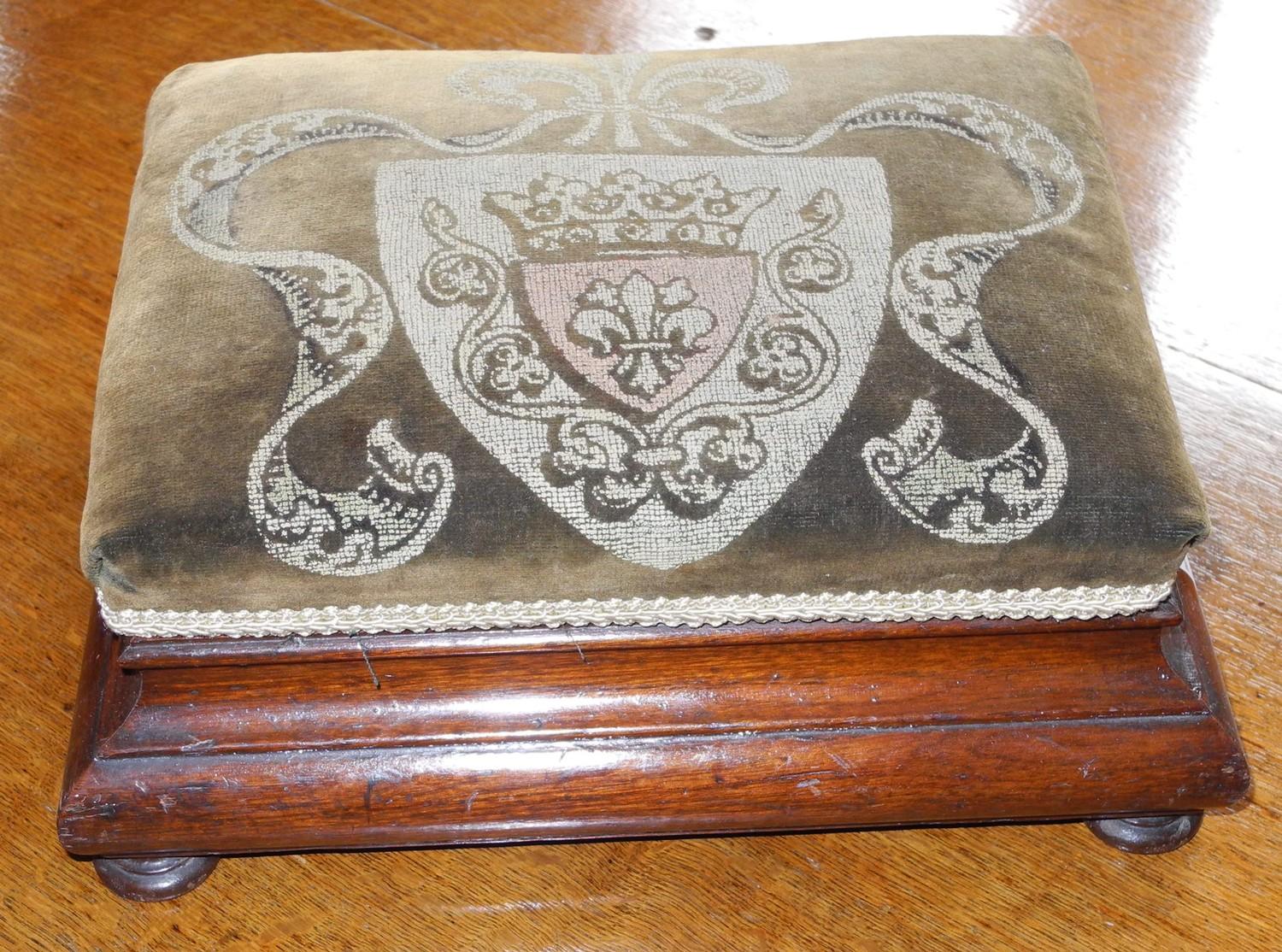 A Victorian foot stool, the velvet top with crest, ogee sides, bun feet, 32cm wide, 25cm deep, c.