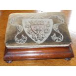 A Victorian foot stool, the velvet top with crest, ogee sides, bun feet, 32cm wide, 25cm deep, c.