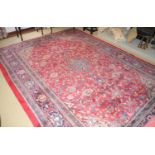 A Middle Eastern woollen rug, with central medallion, and scrolling foliage on a red ground, 315cm