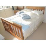 A beech double bed, carved with lozenge to foot board, 140cm wide; pillows, blue silk cushions,