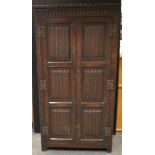 A Priory style wardrobe, nulled frieze, linenfold panelling to doors. 181.5cm high x 95.5cm wide x