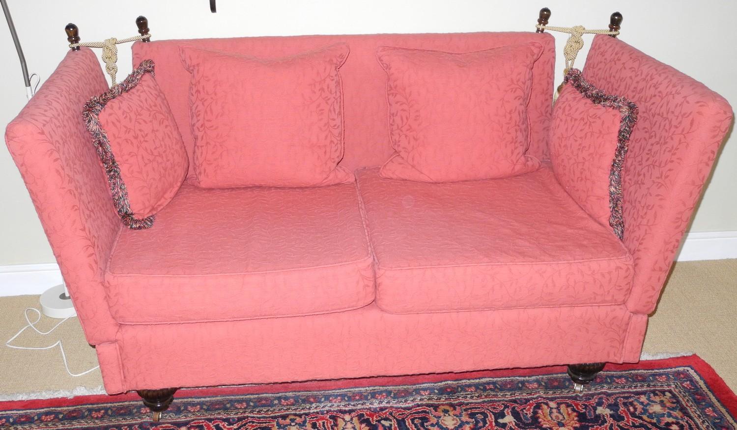 A Knowle sofa, upholstered in rust red, lobed feet, 168cm wide