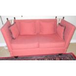 A Knowle sofa, upholstered in rust red, lobed feet, 168cm wide