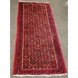 A handwoven runner geometric designs on a red ground 194cm x 81cm; two similar throw rugs, 98cm x