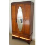 A mid 20th century oak wardrobe, fluted cornice, single door with oval mirror, drawer to base, 194cm