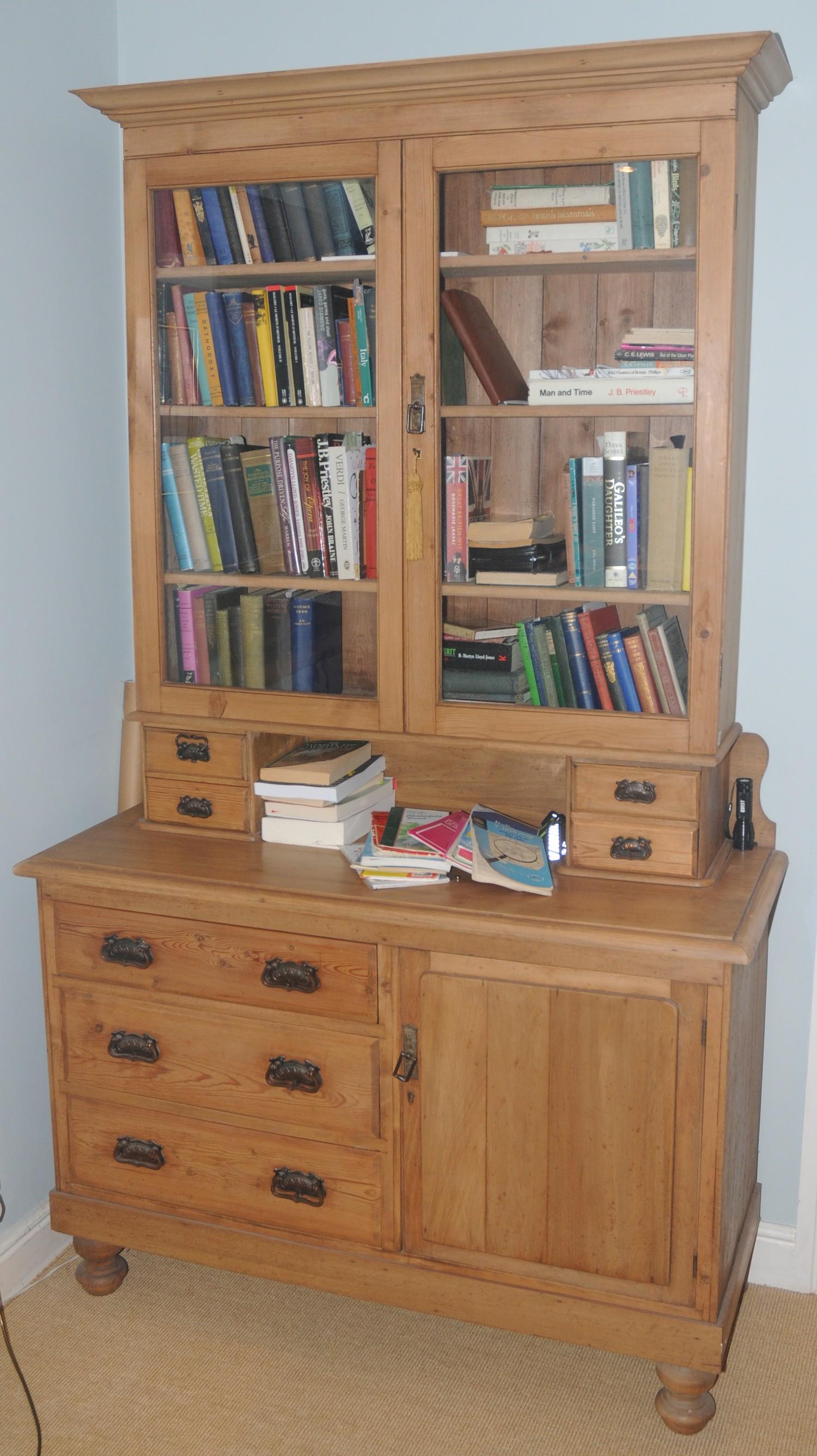 An early 20th century pine bookcase cabinet, with glazed doors, the projecting base with three