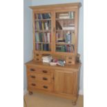 An early 20th century pine bookcase cabinet, with glazed doors, the projecting base with three