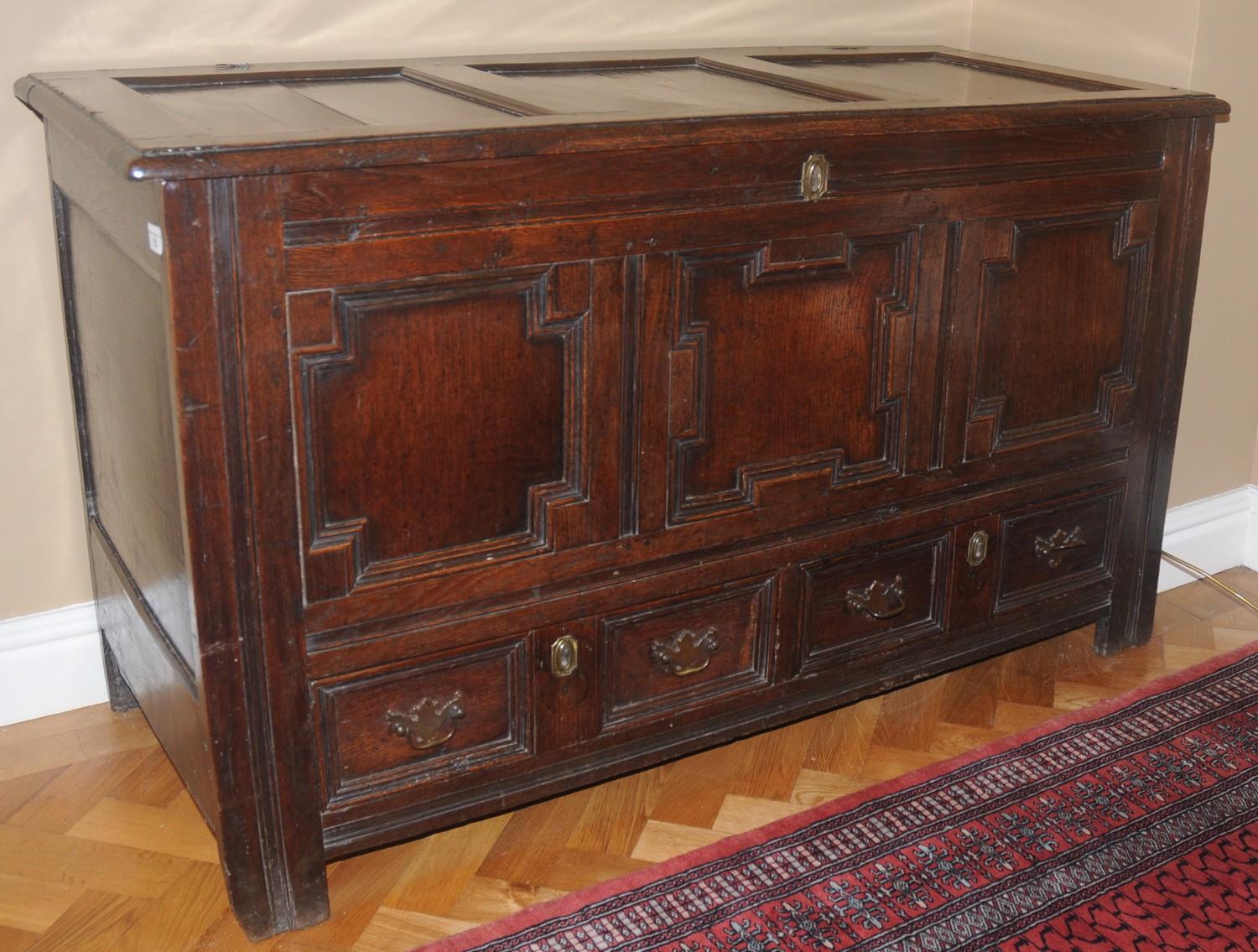 An 18th century oak blanket chest, with panelled top, above field panelled front and two drawers,