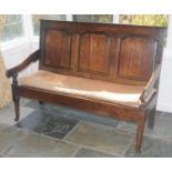 An 18th century oak settle, three fielded panel back, scroll arms, squab seat, tapering