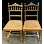 A pair of Edwardian oak salon chairs, wicker seats, turned supports, H-stretcher, c.1910