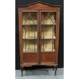 An Edwardian mahogany display cabinet, shaped cresting above a pair of astro glazed doors