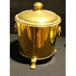 A cylindrical brass coal bucket, domed cover, lion mask handles, three scroll feet, 19th century