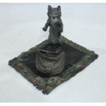 Austrian School (20th century), a cold painted bronze of a cat, stood upon a rug with a satchel bag,