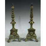 A pair of brass candlesticks, converted for electricity as table lamps, tripod bases, the brass