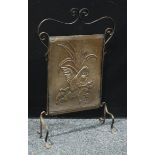 An Arts and Crafts copper and wrought iron fire screen, repousse embossed with a stylised parrot,