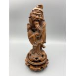 A 19th Century Chinese carved wooden figure in the form of an wiseman or enlarged holding a fish.