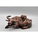 Carved hardwood figurine in the form of a man sitting a water buffalo lying down 22cm long, 9cm high