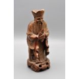 A Chinese carved hardwood figure of Shoulao holding a disc with bone teeth and eyes, 20cm tall