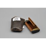 WOODEN SNUFF BOX WITH DECORATED BRASS ENDS IN LEATHER SLEEVE