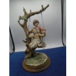 Capodimonte boy and girl on a tree swing on wood plinth, approx 14" high, signed B Merlin c 1883