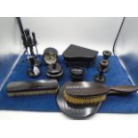 An ebony dressing table set to include a ring stand, candlesticks, clock, piano-shaped jewellery