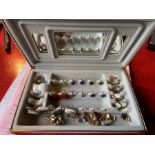 A red velvet jewellery box containing various pair of earrings